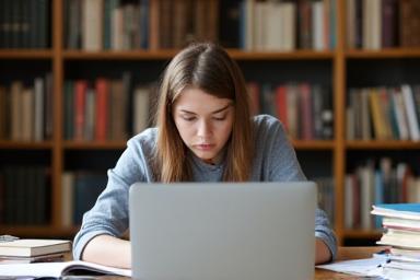 Student studying with textbooks and laptop